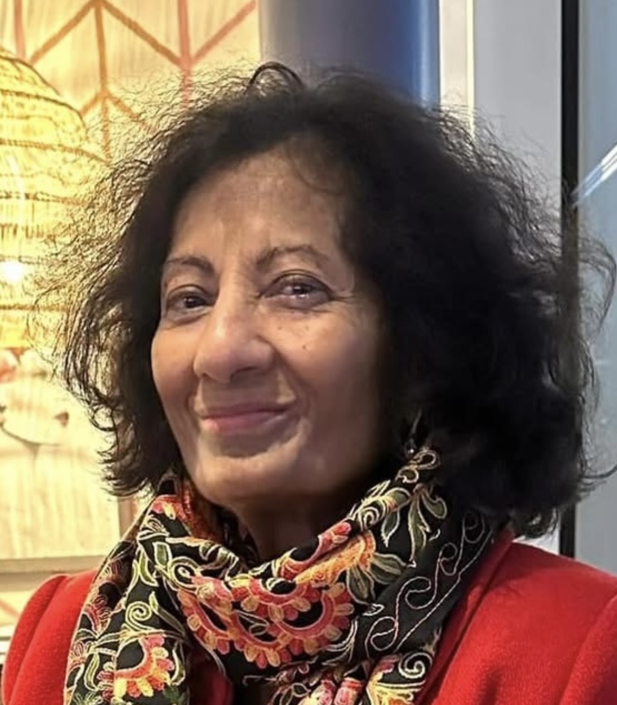 Grace McKee, photographed smiling in a red jacket and patterned scarf.