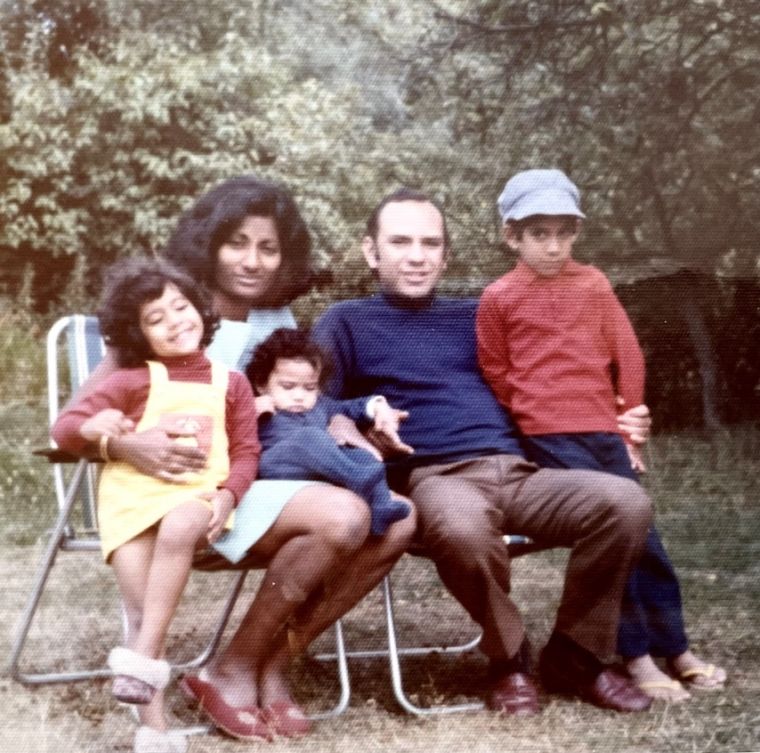 A family group seated outdoors beneath a tree in blossom.
