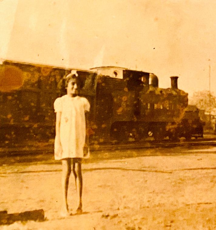 Grace as a small child standing on a platform in front of a steam locomotive in India.